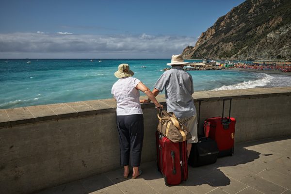 man and woman standing beside concrete seawall looking at beach
